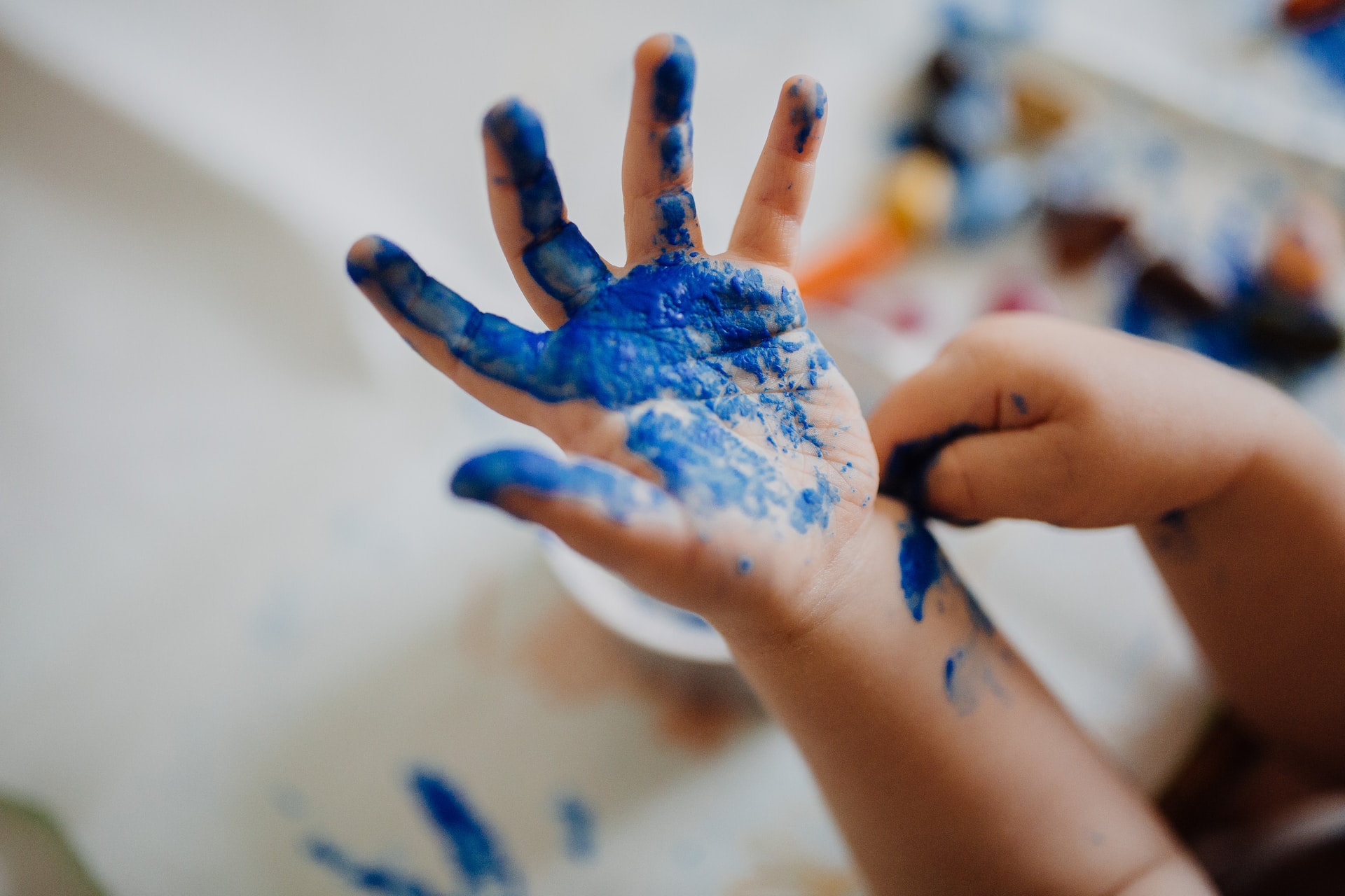 Child with blue paint on their hands