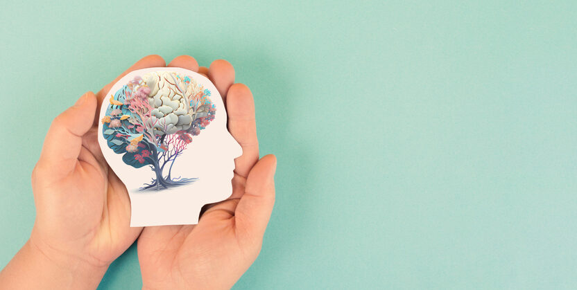 Hands holding paper head, human brain with flowers, self care and mental health concept,
