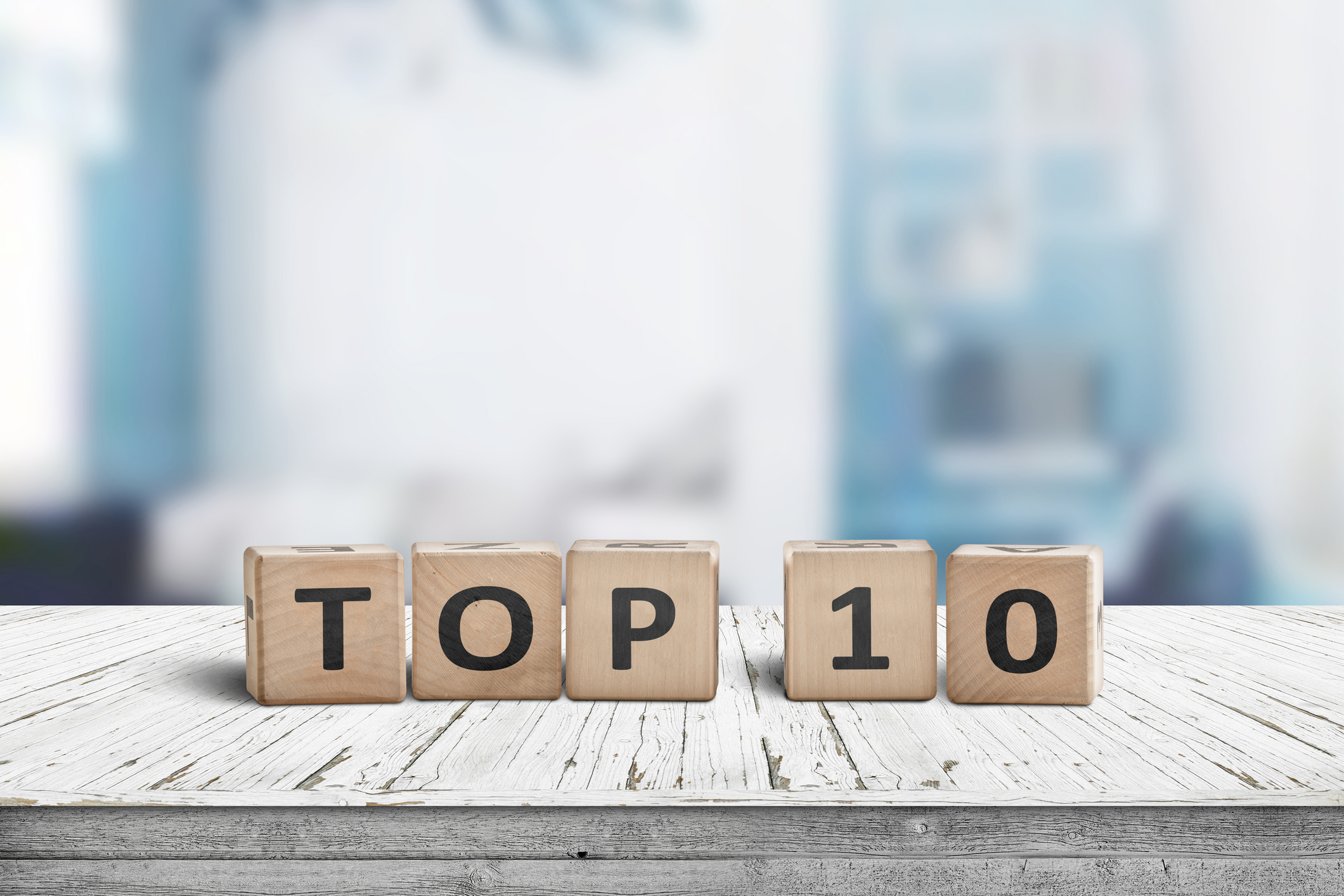Top 10 sign made of wooden blocks on a table in a bright environment with blue colours.